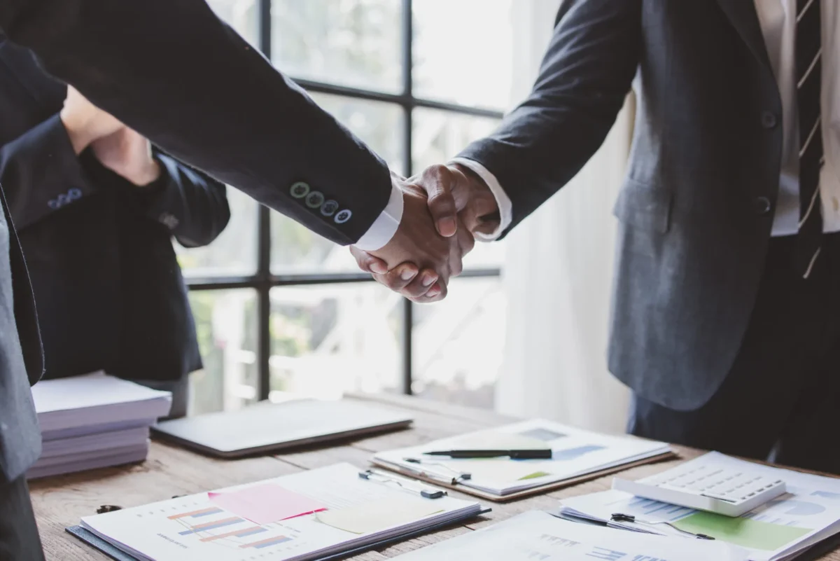 Close-up of a handshake between two professionals over a desk with financial documents